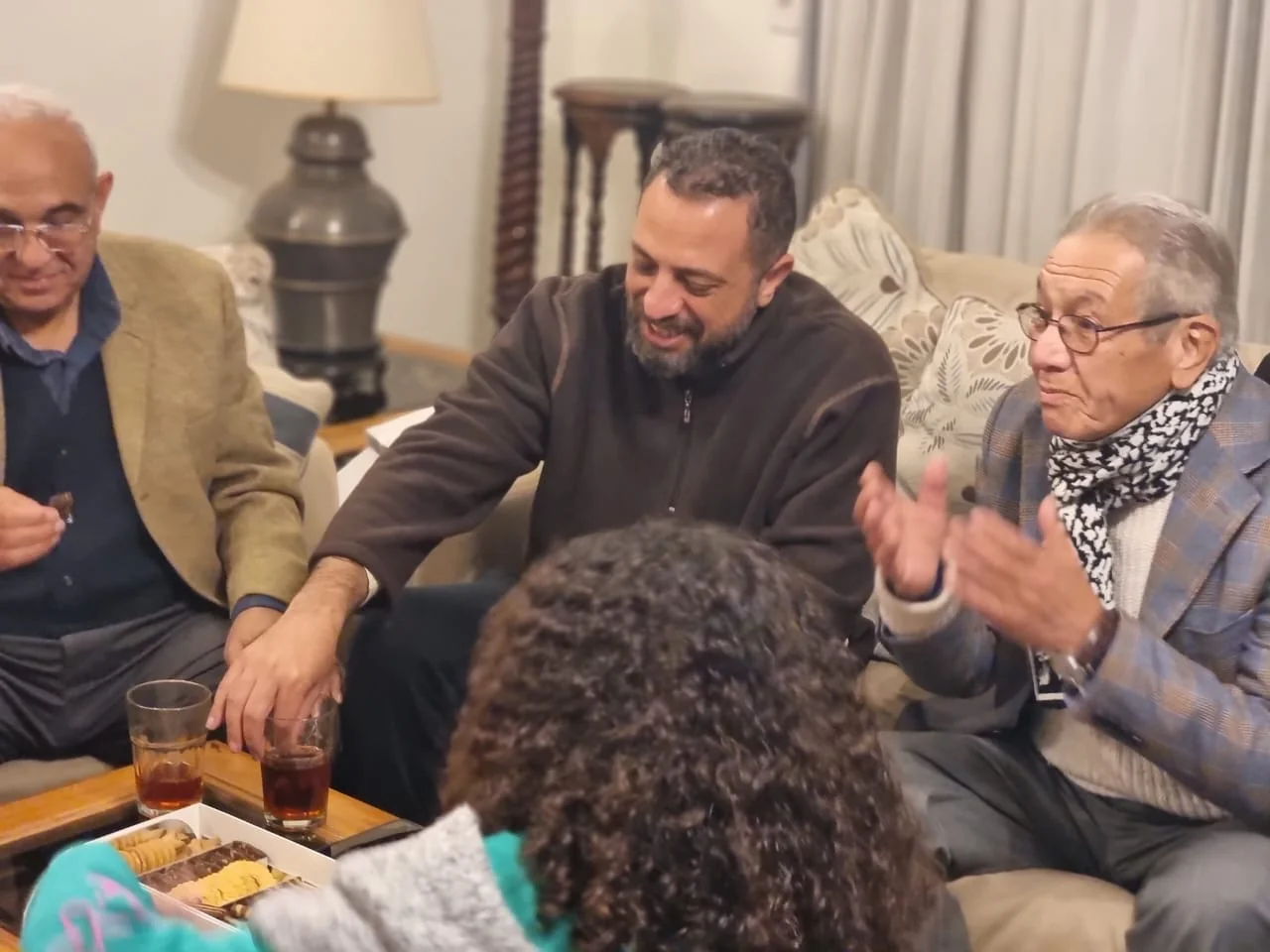 Kamal Ruhayyim speaking with family members during an evening gathering at home