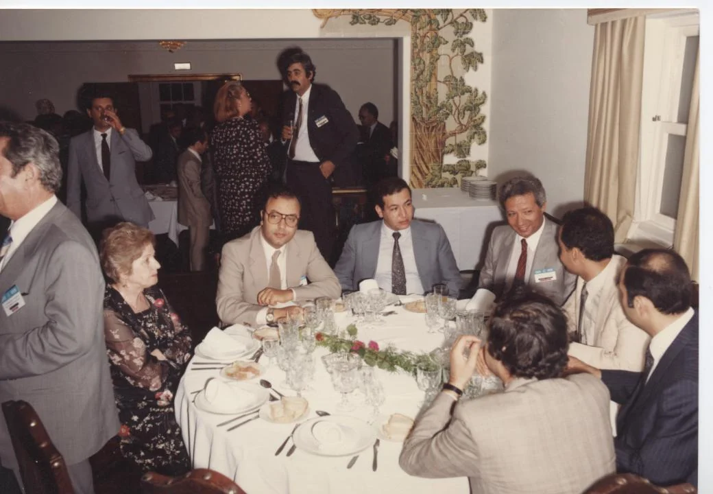 مجموعة من المشاركين تجلس حول مائدة في لقاء خارجي، عام 1984.