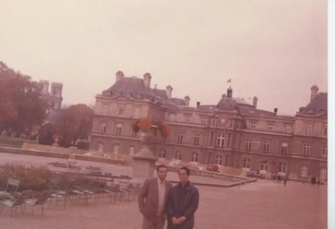Une ancienne photo couleur de deux hommes au jardin du Luxembourg à Paris, en automne, devant le palais du Luxembourg.