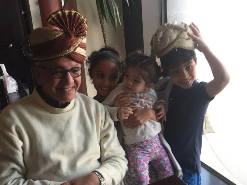 Kamal Ruhayyim lächelt neben drei Enkelkindern bei einem Familientreffen