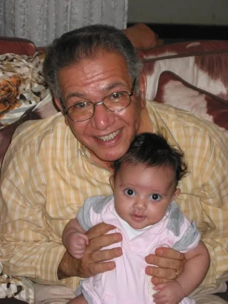 Kamal Ruhayyim souriant en tenant sa petite-fille Kenzy bébé dans ses bras
