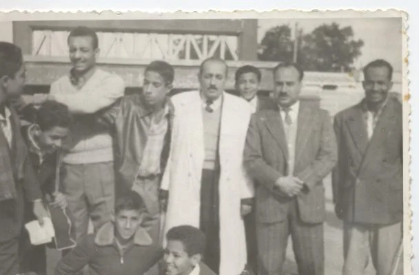 Groupe d’écoliers et de jeunes hommes sur une ancienne photographie en extérieur.